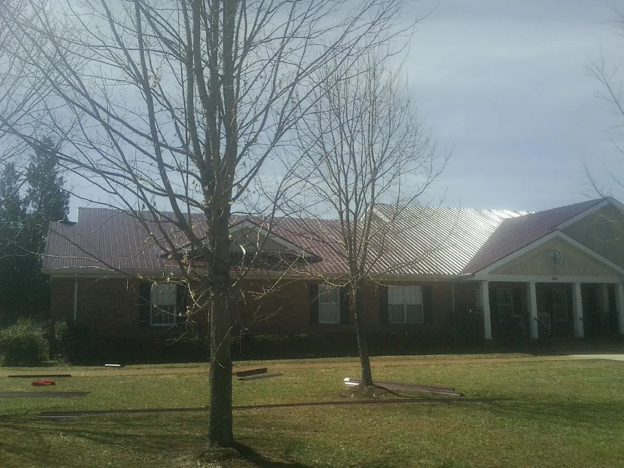 Red metal roof on a brick building seen from the front lawn in Huger