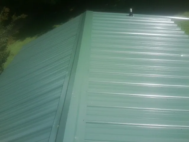 New green metal panels meeting at the ridge of a roof — Flat Roof Repair work by our crew in Huger
