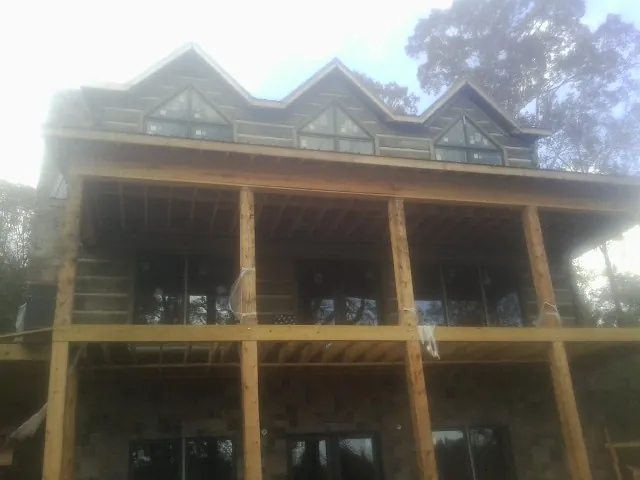 Dormers and porch framing on a large log home under construction — Roof Coating work by our crew in Huger
