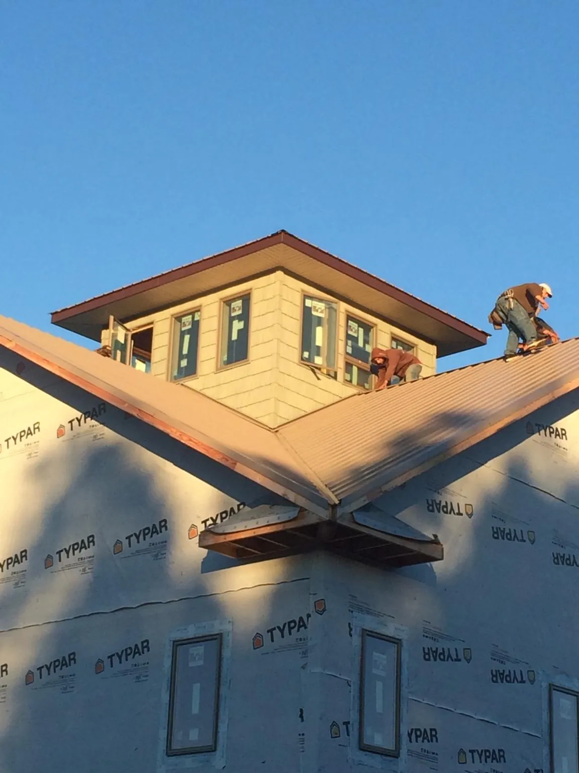 Roofers working around a rooftop cupola on a new metal roof at sunset — Roof Waterproofing in Huger by Roofing Brothers